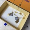 692fd11599f2d84055c89ede A pair of name tags engraved with the classic LV Initials signature, featuring contrasting gold and silver finishes, a soft pearl chain, and a buckle adorned with the LV Circle logo.