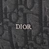 This toiletry bag combines practical functionality with minimalist design. Crafted from black Oblique-print fabric, it features grained calfskin leather trims in matching tones and is adorned with a Dior signature on the front. The front features a zip pocket, a spacious main zipped compartment, and two slip pockets. Equipped with a leather handle, it can be carried by hand or stored inside various handbags.